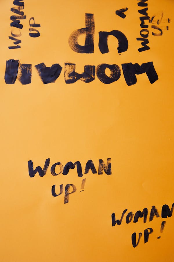From above of inscription Woman up written in black marker on yellow surface