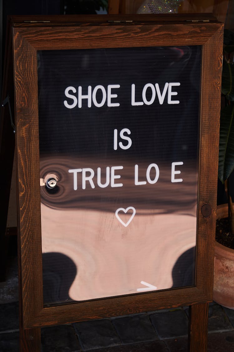 Inscription Shoe Love Is True Love Placed On Mirror In Daytime