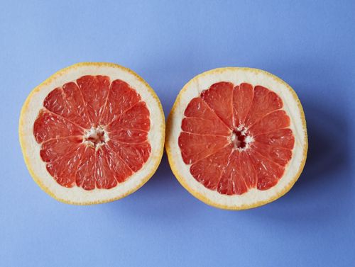 Free Top view of halves of ripe juicy grapefruit placed on purple surface in studio Stock Photo