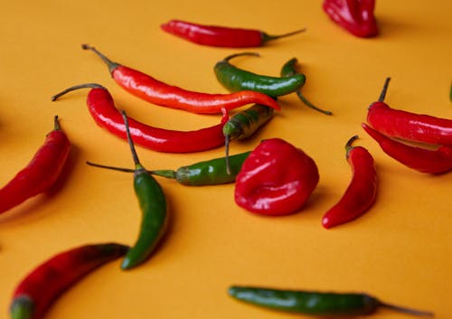 Free Red and green chili peppers scattered on yellow surface Stock Photo
