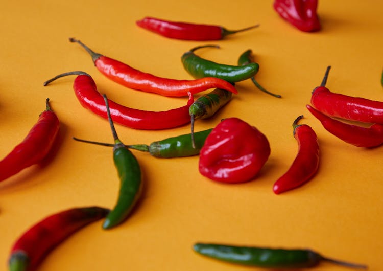 Red And Green Chili Peppers Scattered On Yellow Surface