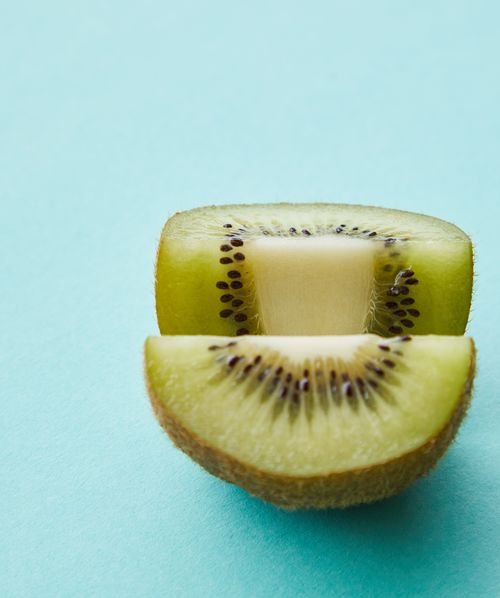 Free From above of sliced sweet ripe tropical kiwi with black seeds placed on light blue background Stock Photo