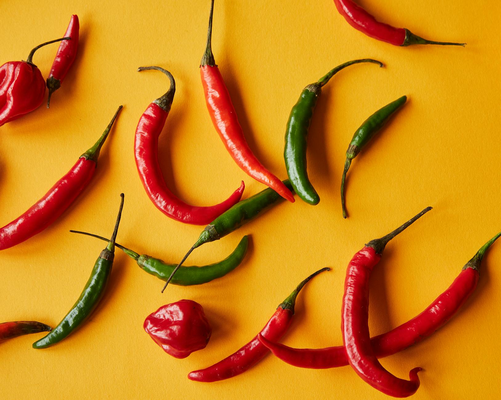 Red and green peppers on yellow background