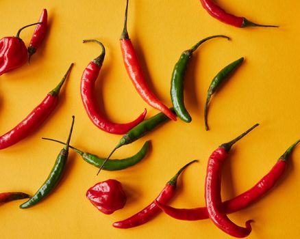 Fresh red and green chili peppers spread across a yellow background, capturing vibrant colors and spicy allure.