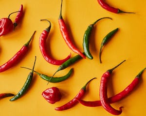 Red and green peppers on yellow background
