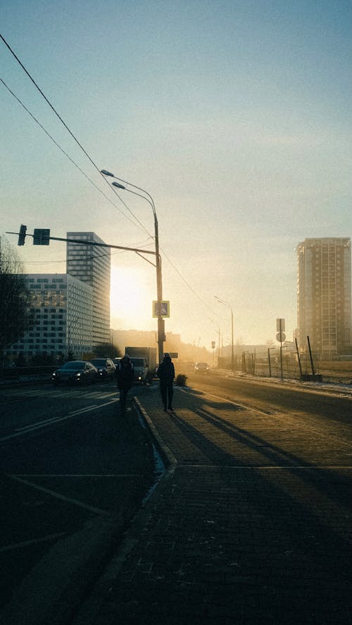 Silhouettes of people walking along asphalt road in morning