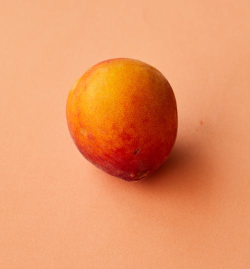 High angle of whole healthy ripe peach placed on beige background in studio
