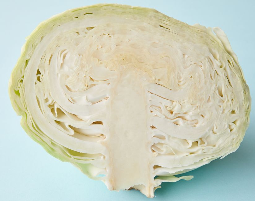 Cross-section of a whole green cabbage cut in half, showing its tightly packed pale leaves