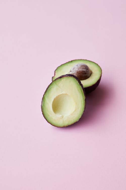 Kostenlos Geschnittene Avocado Frucht Auf Rosa Oberfläche Stock-Foto