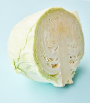 Close-up of a halved cabbage on a light blue background, showcasing its fresh and healthy appeal.