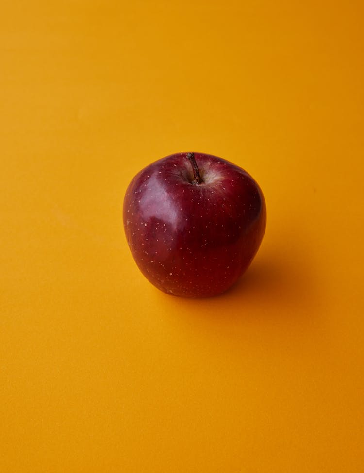 Ripe Shiny Red Apple Placed On Yellow Surface