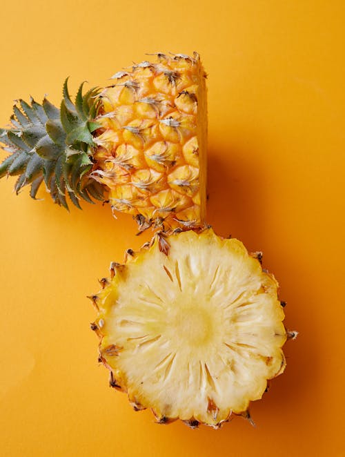 Top view of fresh ripe sweet halved pineapple placed on bright yellow surface