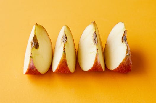 Sliced apples arranged in a row on a bright yellow background, showcasing freshness and simplicity.
