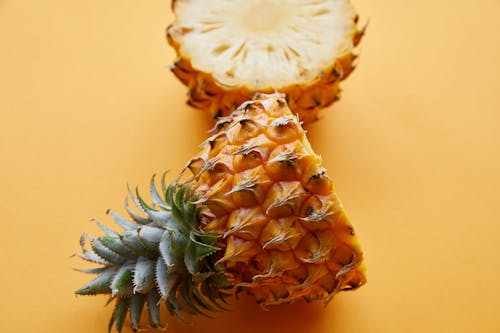 From above of fresh textured half cut pineapple on bright yellow background of studio