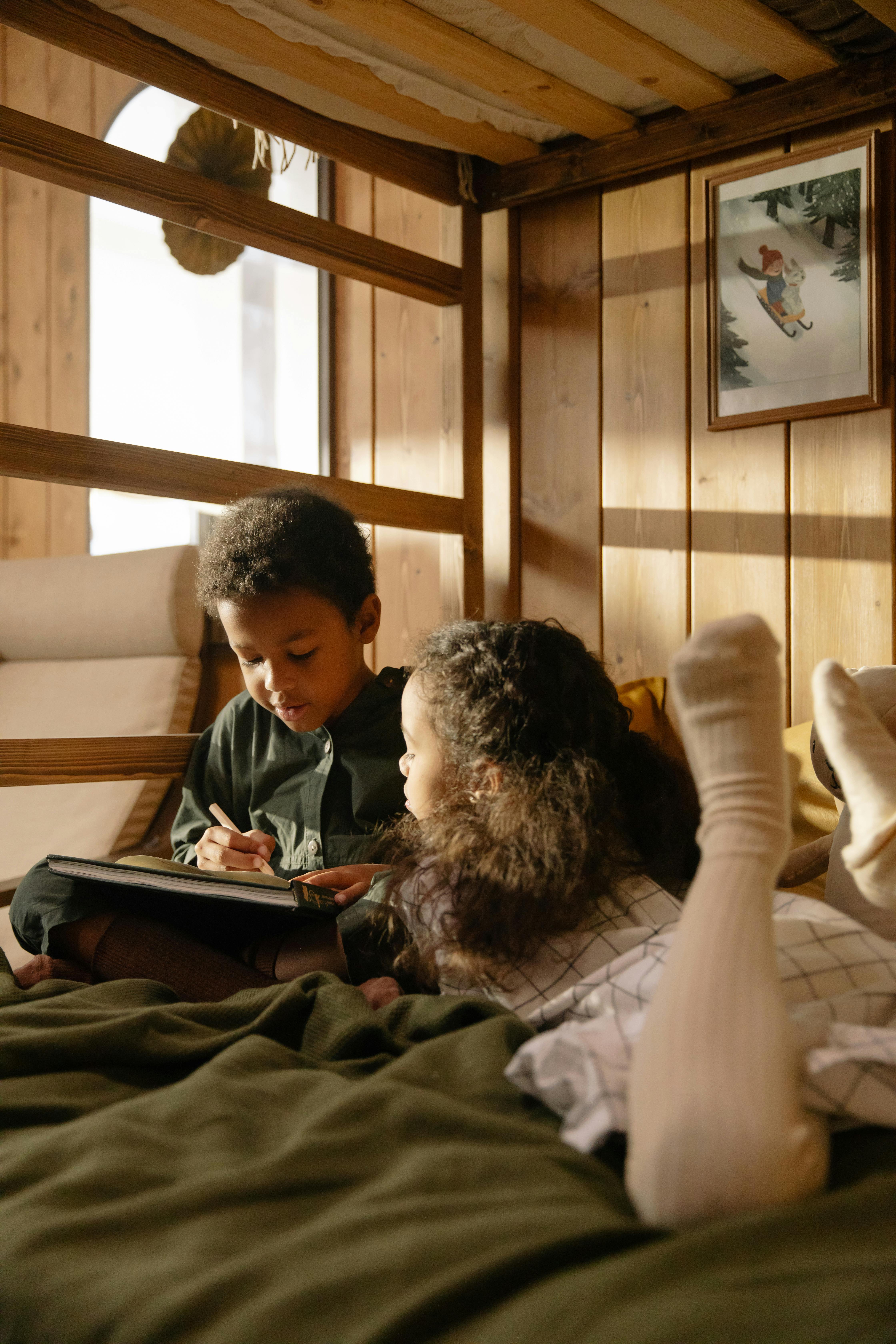 a girl watching her brother write on a book