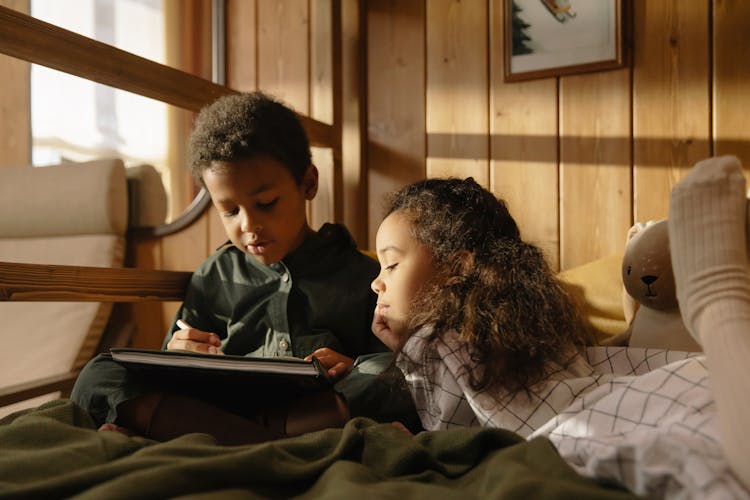 A Girl Watching Her Brother Write On A Book