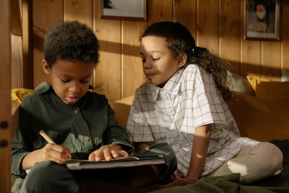 Dos niños disfrutan de un tiempo creativo en el interior, dibujando y uniéndose bajo la acogedora luz del sol.