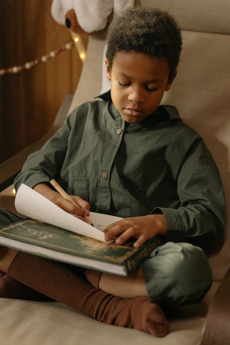 A Boy Writing On A Paper