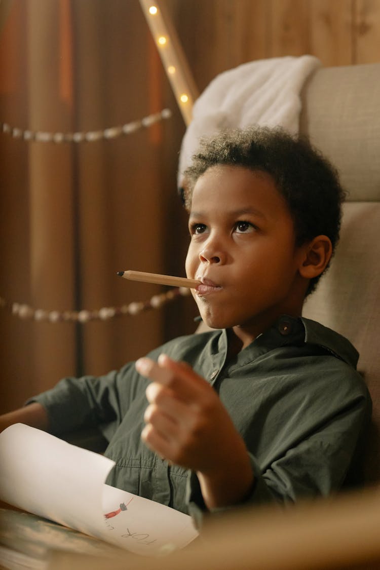 A Boy Biting A Pencil