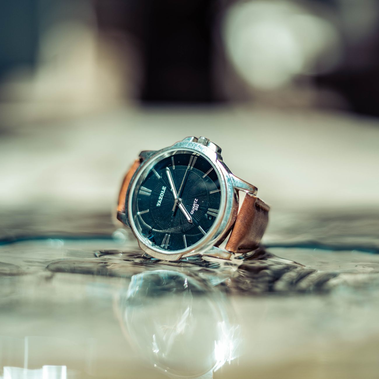 Close-up of a luxury wristwatch with a leather strap on a reflective surface, showcasing elegance.