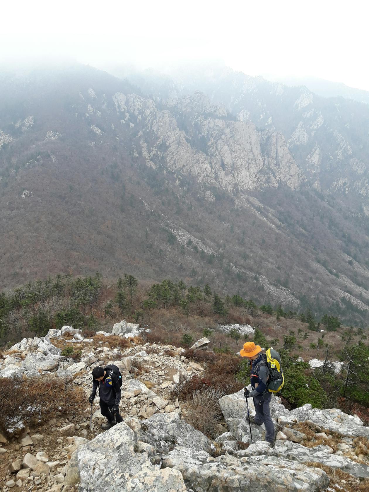 Hikers on a rocky mountain trail in South Korea with dramatic peaks in the background