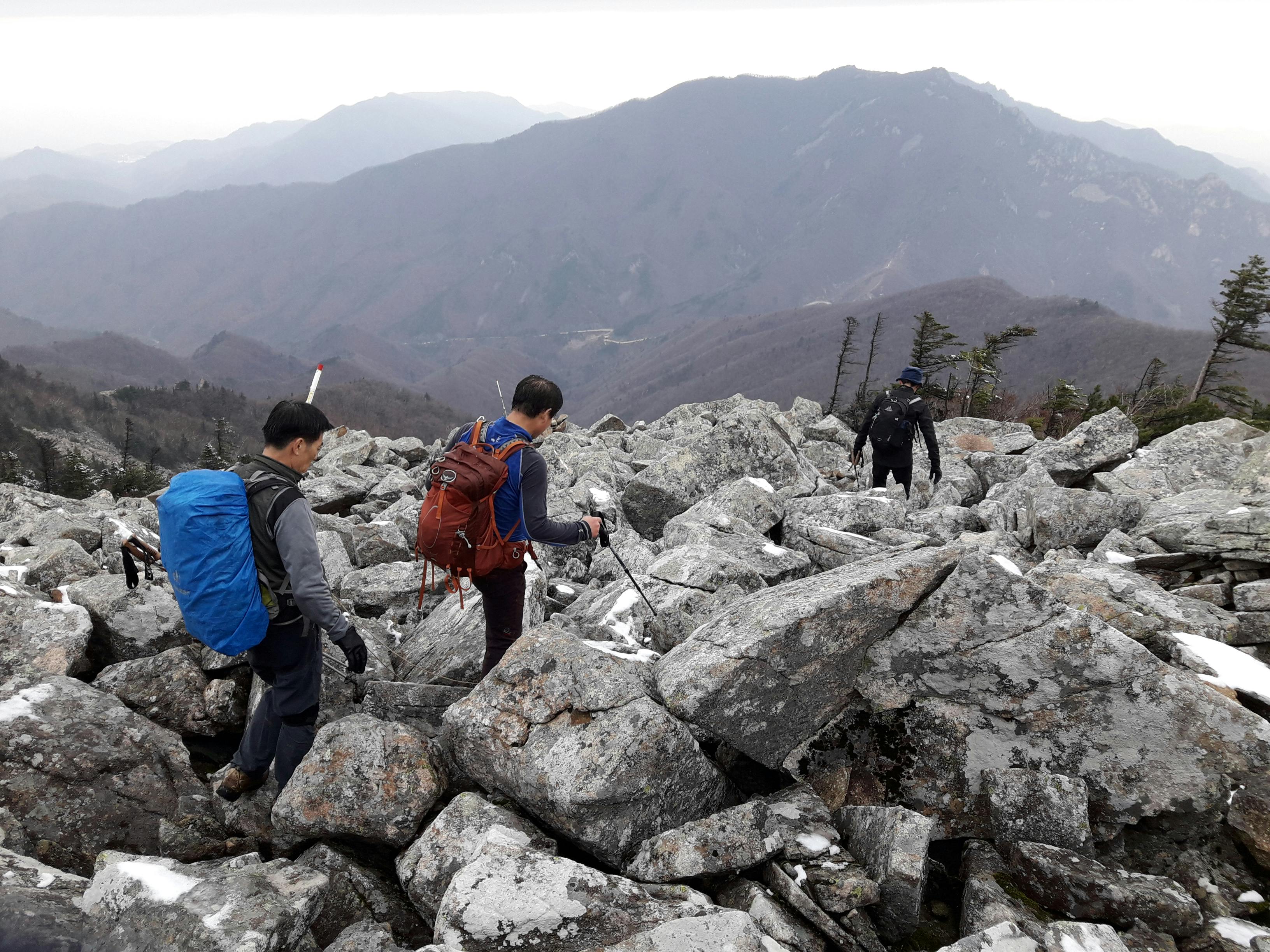 Hikers traverse a rocky trail with stunning mountain views in Sokcho, South Korea.