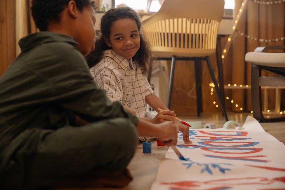 Two children enjoying arts and crafts indoors, painting with enthusiasm and creativity.