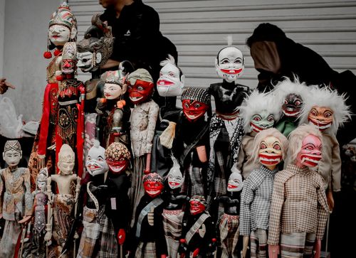 Free Unique collection of vibrant traditional puppets with expressive faces on display outdoors. Stock Photo