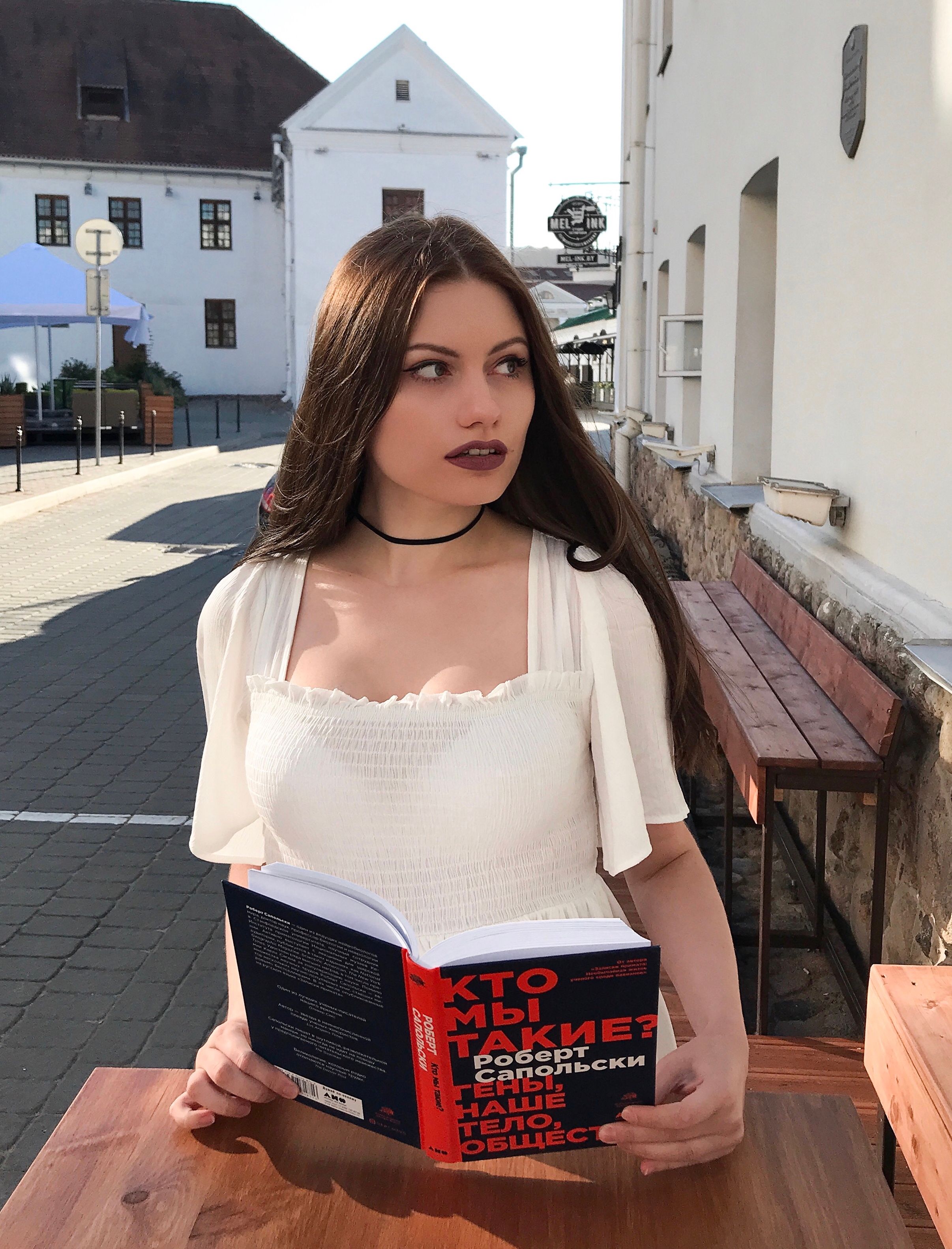 Young woman reading outdoors in Minsk, Belarus with a captivating book and modern style.