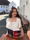 A Woman in White Shirt Holding a Book