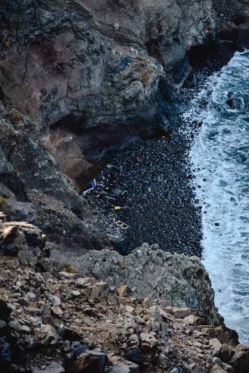 Человек в синей рубашке, стоящий на скалистом берегу