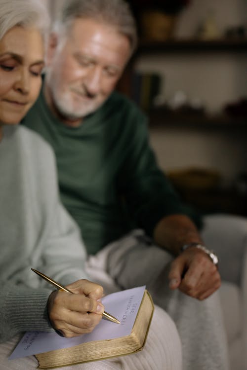 Free Elderly Woman sitting beside her Husband writing on a Paper  Stock Photo