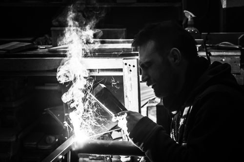 Free A grayscale image of a welder at work, capturing sparks and smoke in a workshop. Stock Photo