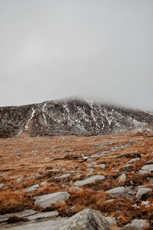 Foggy Mountain Landscape with Brown Grass on a Rocky Slope