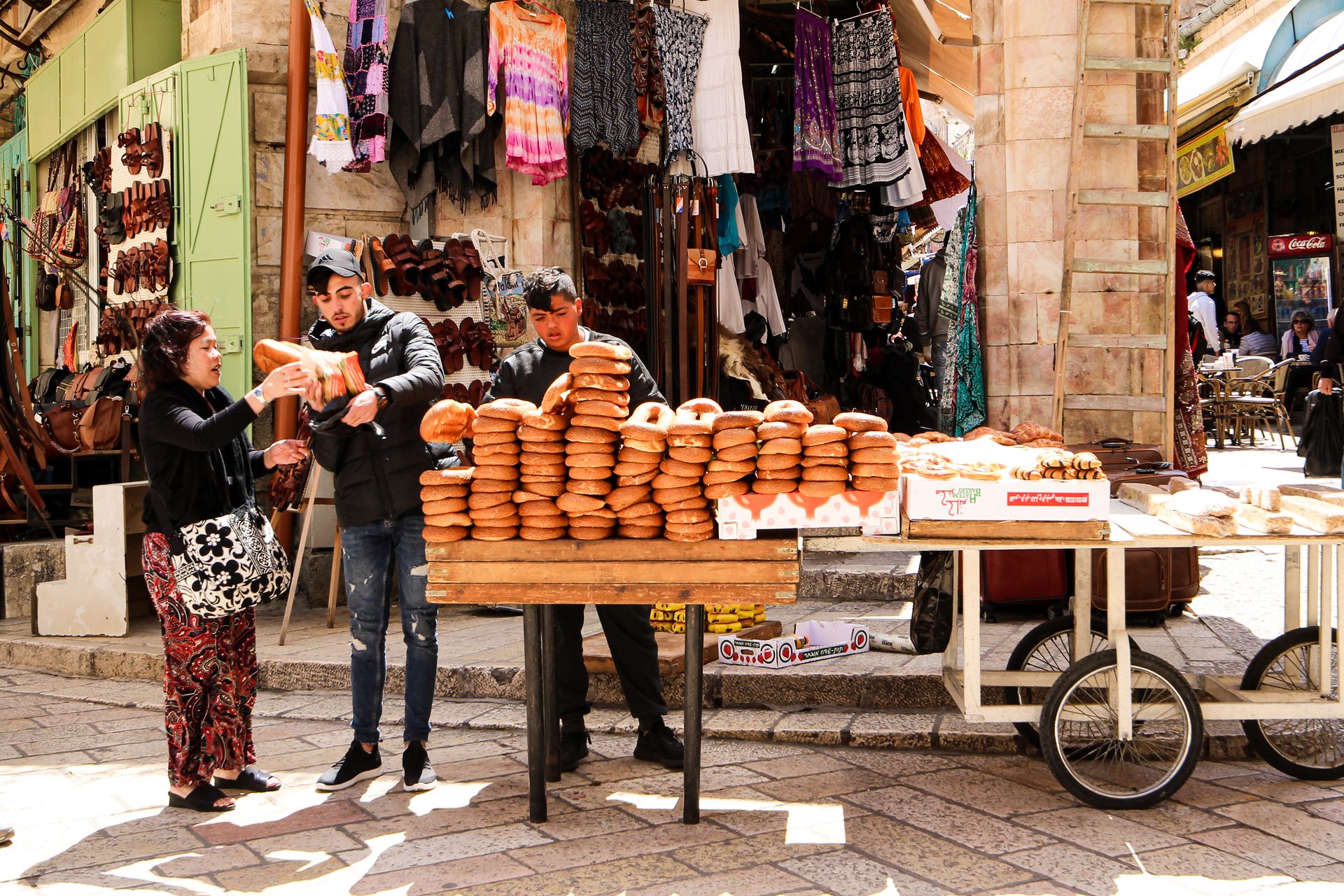 Explore the bustling street market in Jerusalem with vendors selling fresh bread and vibrant textiles.