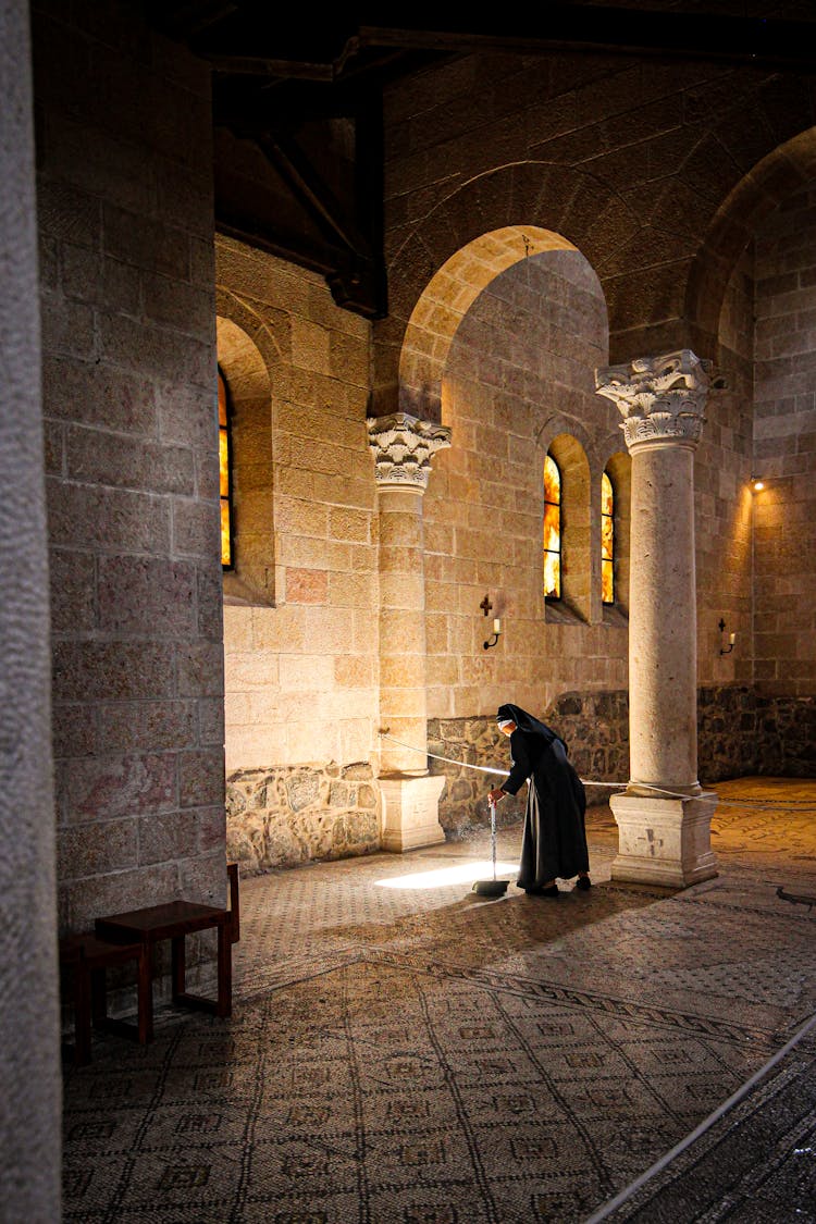 Nun Swiping Floor In An Illuminated Monastery