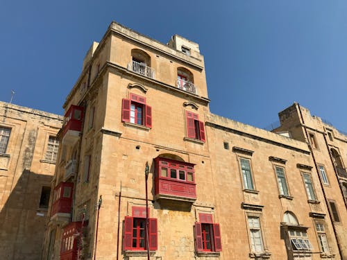 Low Angle View of Beige Architecture with Red Balconies and Window Shutters