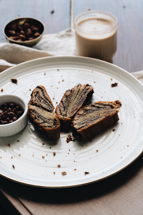 Vertical Shot of Strudel Cake Slices on a White Plate, Latte and Hazelnuts 