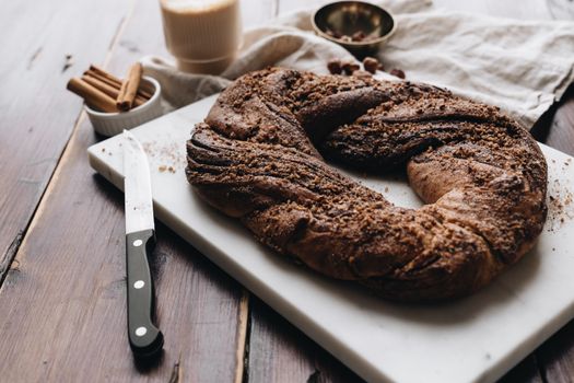 Top view of a chocolate babka on a marble board with a knife and spices, perfect for bakery-themed content.