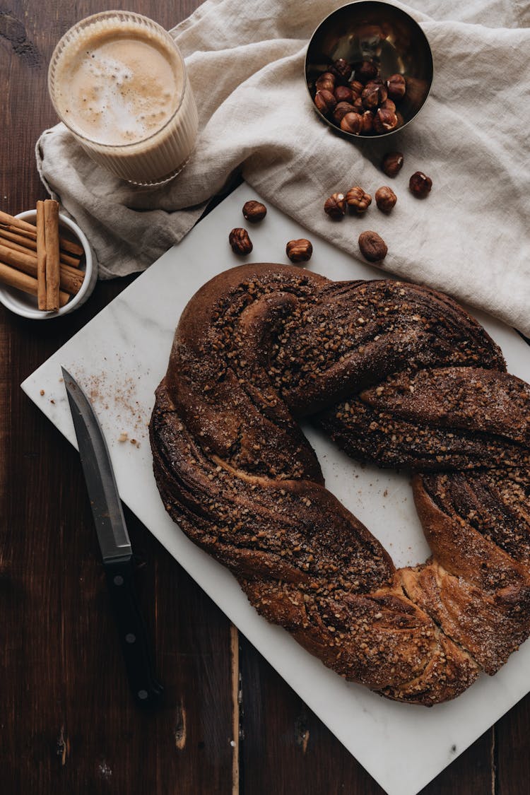 Top View Of A Brown Strudel, Hazelnuts, Cinnamon Sticks And Coffee Latte