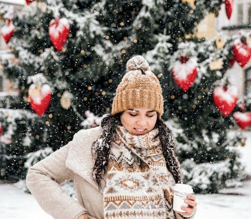 Free Woman in White Sweater and Brown Knit Cap Sitting on Snow Covered Ground Stock Photo