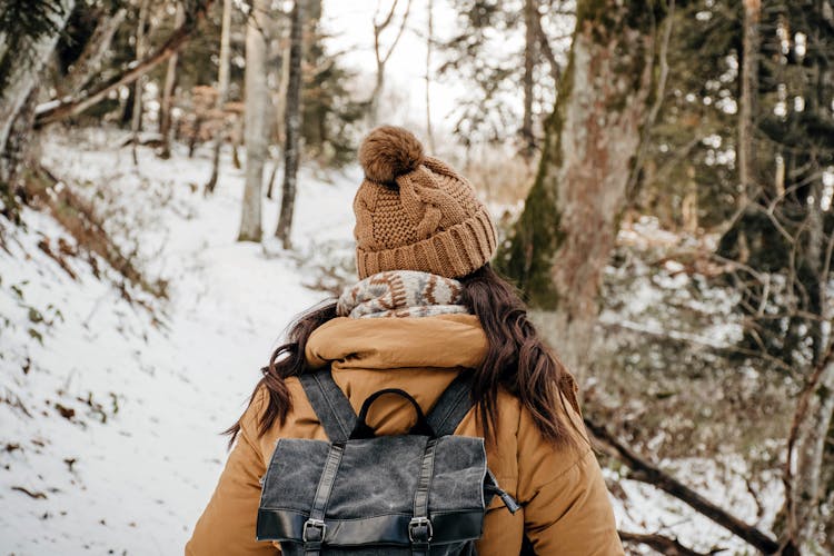 Woman In Brown Jacket And Black Backpack Standing On Snow Covered Ground