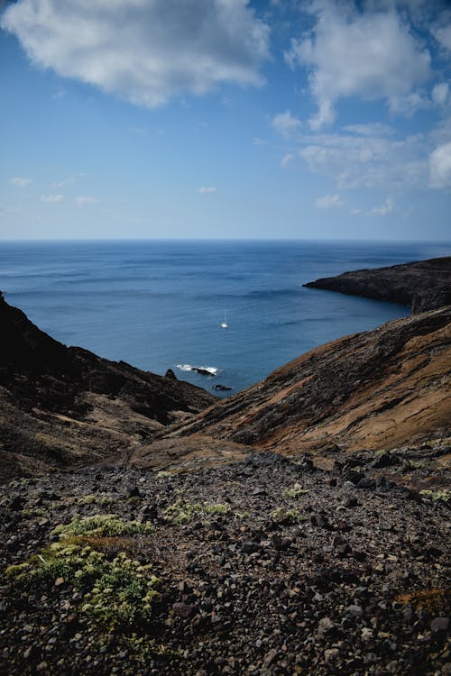 Barco Blanco En El Mar Cerca De La Montaña Marrón Bajo Un Cielo Azul