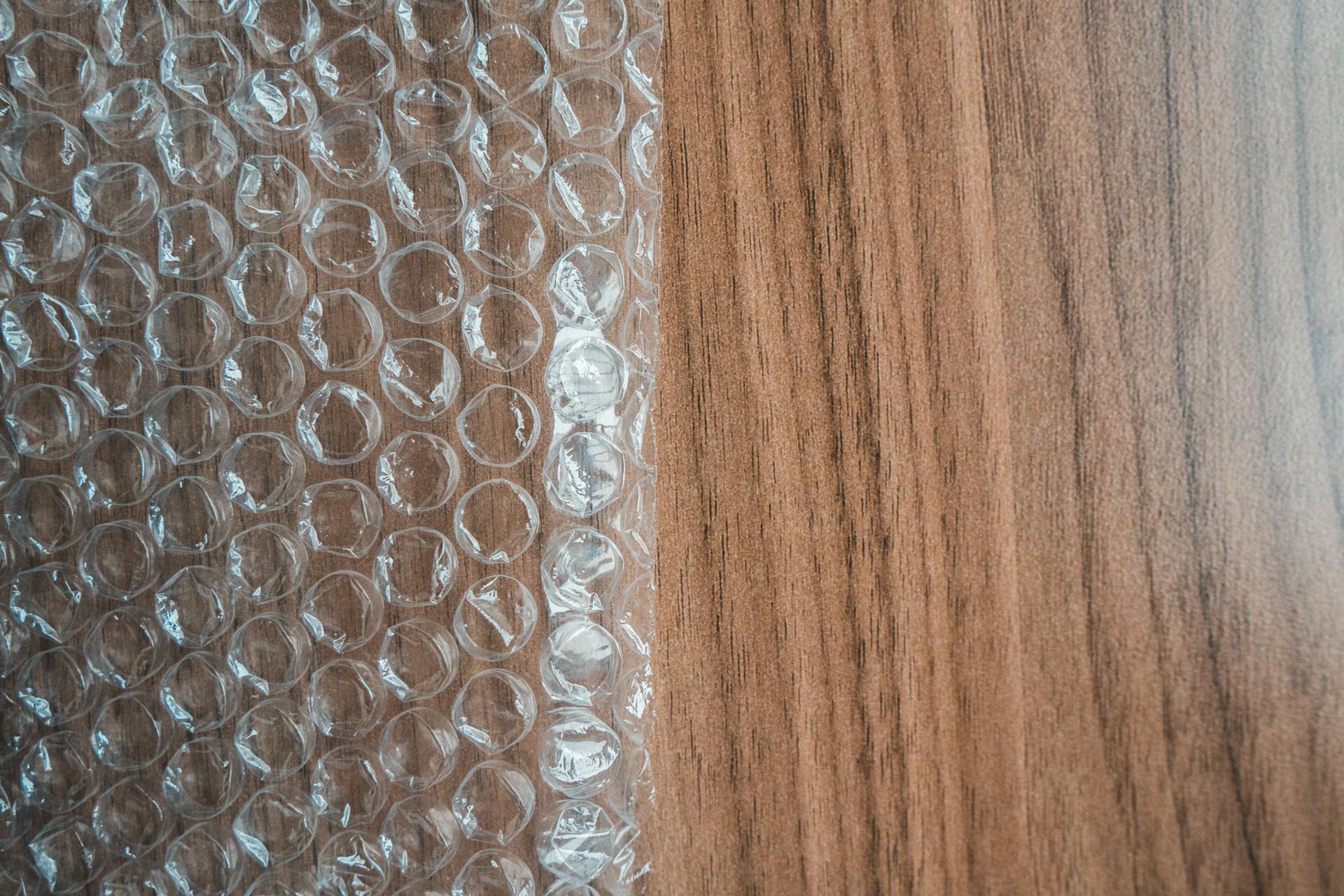 Top view of bubble wrap sheet with uneven surface on smooth wooden desk in shiny light