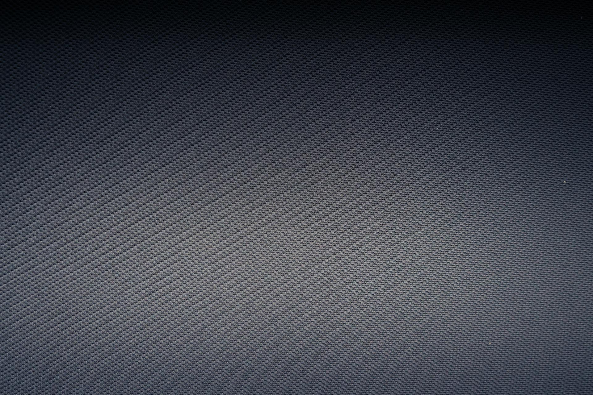 Textured background of carbon fiber fabric with tiny holes