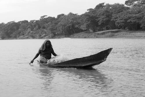 Grayscale Photo of a Man Riding a Boat
