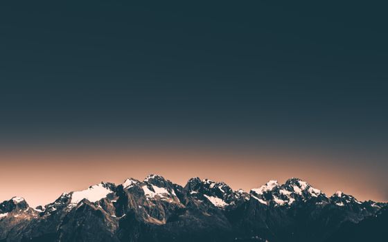 Beautiful snow-covered mountain range in New Zealand with a clear twilight sky.