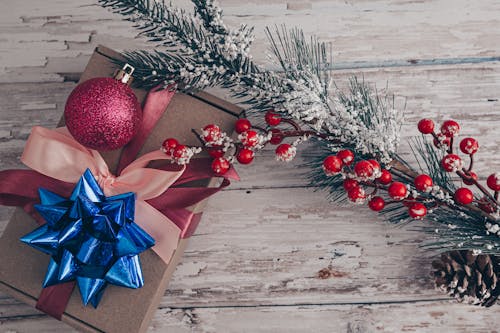 Xmas gift box with bauble and fir tree branch on wooden table