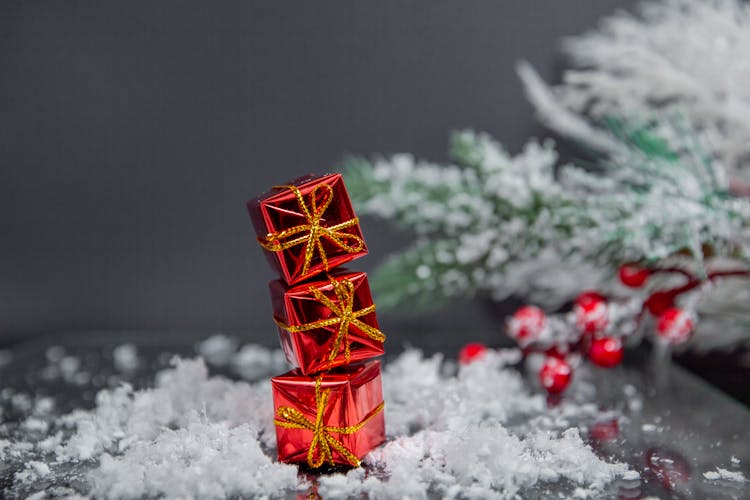 Small Christmas Red Present Boxes Placed On Table Near Snowy Spruce