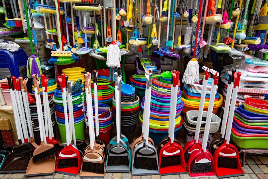 From above various sets of broom and scoop placed in household goods store near colorful basins and bins